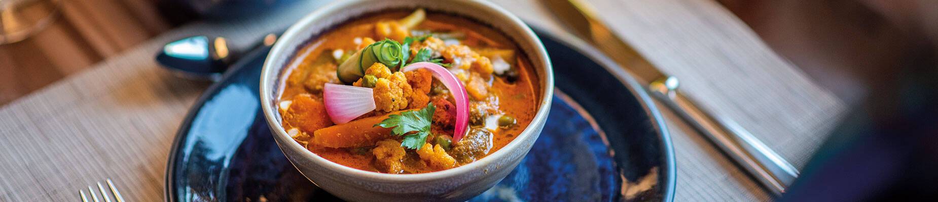 A person sitting in front of a curry on a table