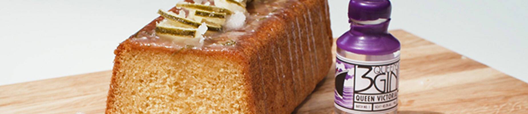 Drizzle cake on a wooden chopping board with a bottle of gin