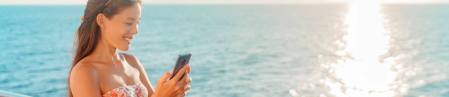 Person holding a phone while looking out at sea
