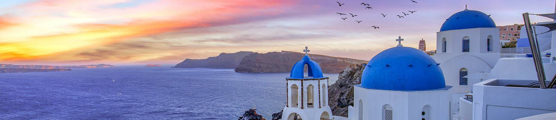 The sun setting over Santorini as birds fly