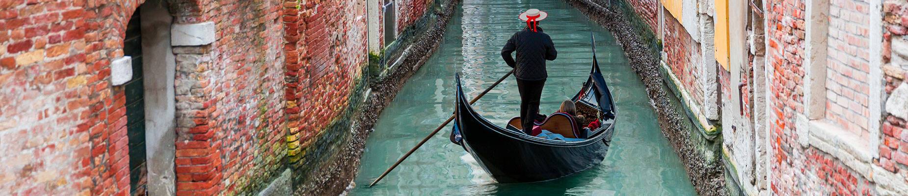 Venetian gondolier punting through Venice