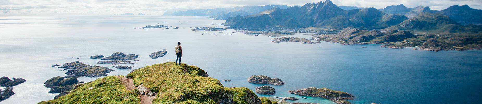 Person on a cliff’s edge looking over a fjord