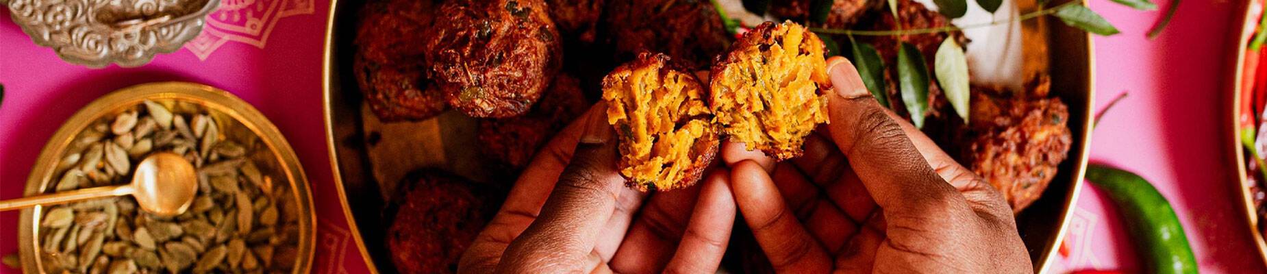 Two hands breaking food over a gold plate